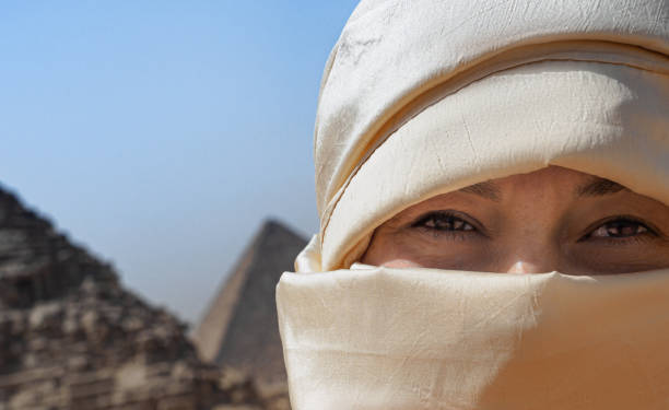 Fragment of the face of a woman wrapped in a beige silk scarf Fragment of the face of a woman wrapped in a beige silk scarf against the background of the pyramids of Giza, Cairo, Egypt. hot egyptian women stock pictures, royalty-free photos & images