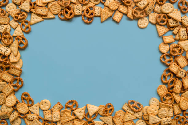 Frame of a lot of mini crackers with poppy seeds and salt crystals on a blue background, flat lay stock photo