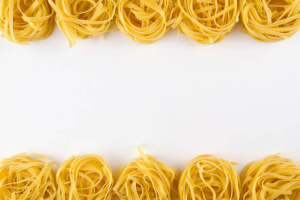 Frame of Italian Pasta Tagliatelle Frame of Italian pasta Tagliatte isolated on white background. There are two stripe of tagliatelle in this photograph. One is in lower edge, the other one was used in upper edge. uncooked pasta stock pictures, royalty-free photos & images