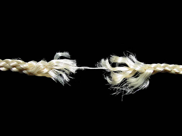 Frayed rope breaking apart at the last strand stock photo