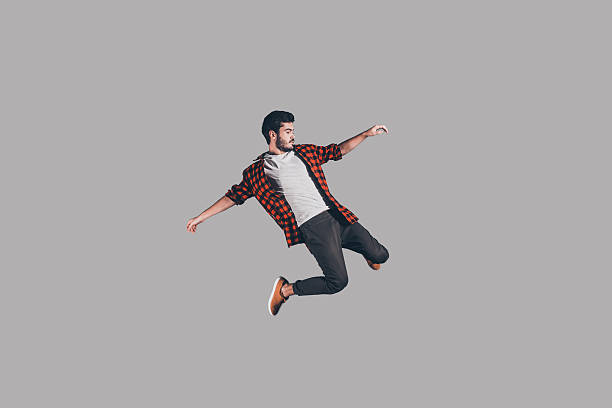 Freedom in every move. Mid-air shot of handsome young man jumping and gesturing against background levitation stock pictures, royalty-free photos & images