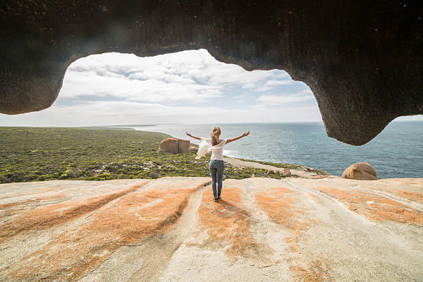 Freedom in nature Cheerful young woman arms outstretched at The Remarkable rocks, located in Flinder's  chase National park on Kangaroo Island, SA, Australia. south australia stock pictures, royalty-free photos & images
