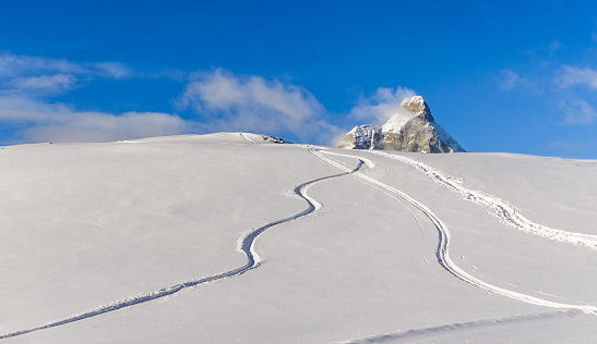 Freeride tracks on powder snow with mountain peak background