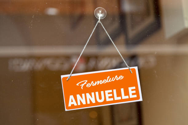 Blue sign open sign hanging at the glass door of a shop saying in French: "Fermeture Annuelle", meaning in English: "Annual closure".