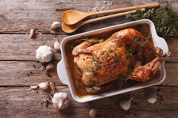 French Food: Chicken with 40 cloves of garlic French Food: Chicken with forty cloves of garlic in the dish for baking and ingredients close-up on the table. horizontal view from above french food photos stock pictures, royalty-free photos & images