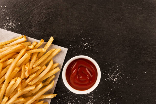 French fries with ketchup on dark background, directly above. stock photo