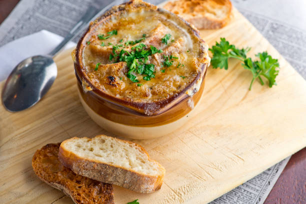 French onion Soup. Classic French or American restaurant or diner favorite. Beef broth, onions, Diced vegetables, celery, carrots, onions, garlic, sautéed in olive oil & slow cooked. Topped with melted cheese and served with toasted baguettes. stock photo
