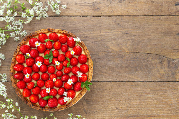 French strawberry tart surrounded by white flower on oak wood background. Flat Lay, top view with copy space. stock photo