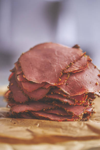 Fresh and delicious stack of sliced pastrami meat placed on wooden cutting board stock photo