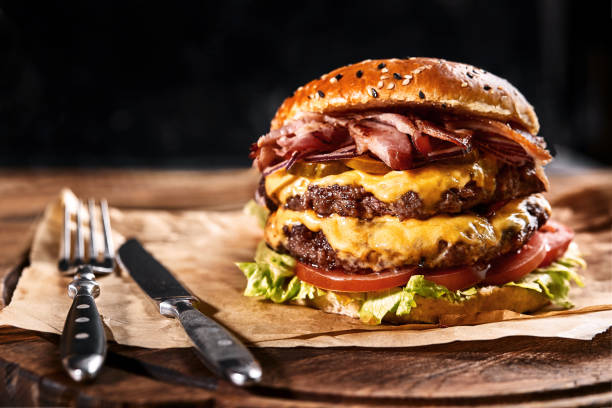 나무 테이블에 맥주와 종이 베개에 신선하고 육즙 햄버거. 어두운 배경, 전통적인 미국 음식. 정크 푸드 - burger 뉴스 사진 이미지