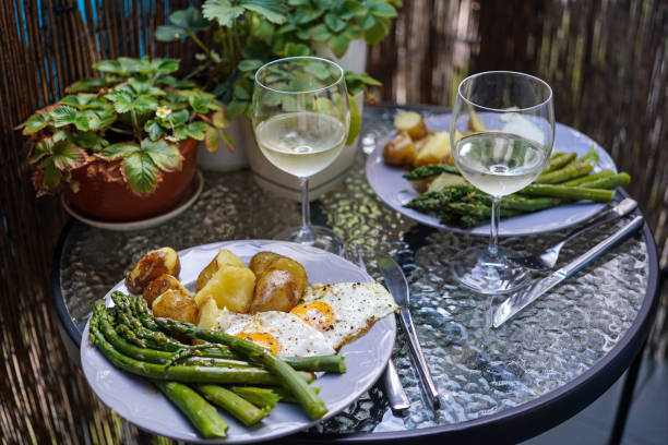 fresh asparagus with young boiled potatoes, fried egg and glass of white wine stock photo