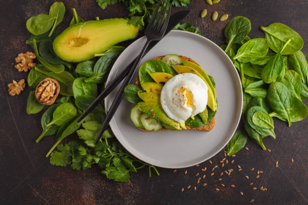 Fresh avocado breakfast with egg poached sandwich. Green salad and seeds, healthy vegetarian food concept. Food background. Top view, copy space. Fresh avocado breakfast with egg benedict sandwich. Green salad and seeds, healthy vegetarian food concept. Food background. Top view, copy space. poached food stock pictures, royalty-free photos & images