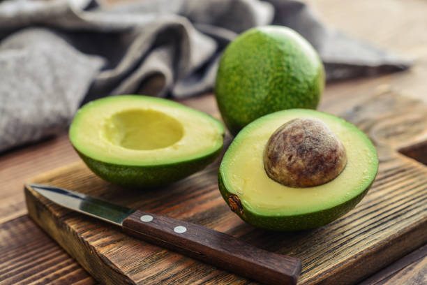 Fresh avocado on cutting board Fresh avocado on cutting board over wooden background avocado stock pictures, royalty-free photos & images
