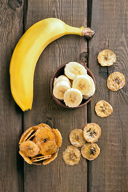 Fresh bananas and chips on wooden table, top view. Focus on fresh...