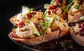 Fresh bruschettas pate in plate on black wooden table background
