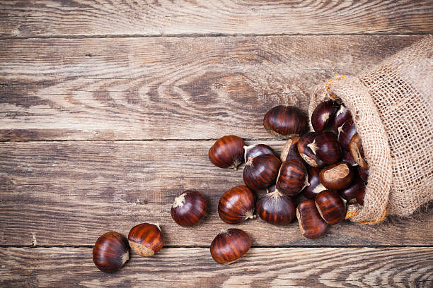 Fresh chestnuts in sack bag Fresh chestnuts in sack bag on the old wooden table chestnut food stock pictures, royalty-free photos & images