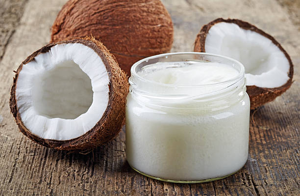 Fresh coconuts and a jar of coconut oil on a wooden table stock photo