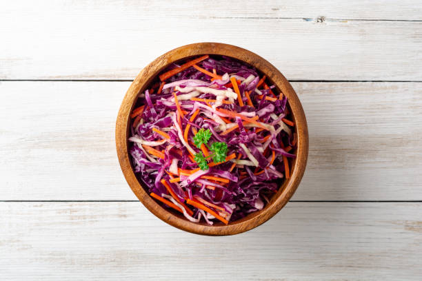 Fresh coleslaw salad with red and white cabbage and carrots in bowl on white wooden background stock photo