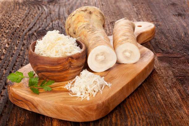 Fresh grated horseradish Fresh and grated horseradish in wooden bowl with parsley on wooden cutting board. Horse-radish root. horseradish stock pictures, royalty-free photos & images