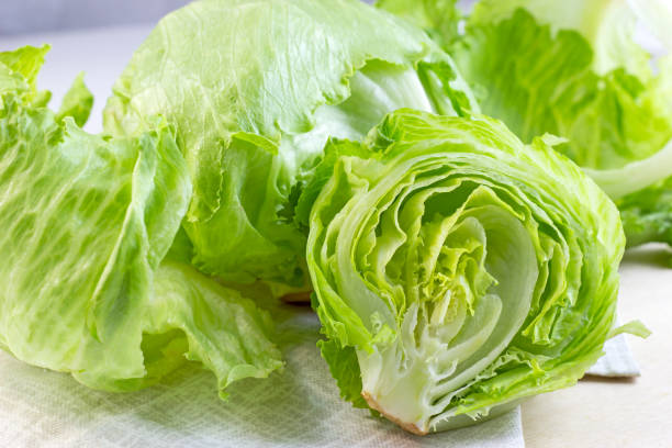 Fresh green iceberg lettuce salad leaves cut on light background on the table in the kitchen stock photo