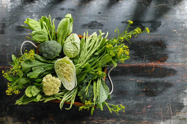 Fresh green leaf vegetables in an old wooden crate on an old wooden table. stock photo