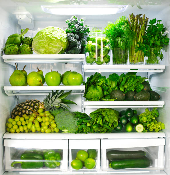 Fresh green vegetables and fruits in fridge. stock photo