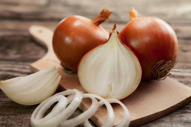 Fresh healthy onions on chopping board Fresh healthy onions and one sliced onion on chopping board onion stock pictures, royalty-free photos & images