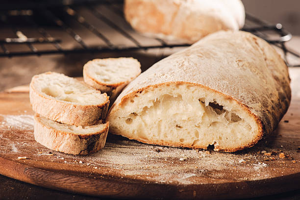 fresh italian bread on a cutting board - gebakken in de oven stockfoto's en -beelden