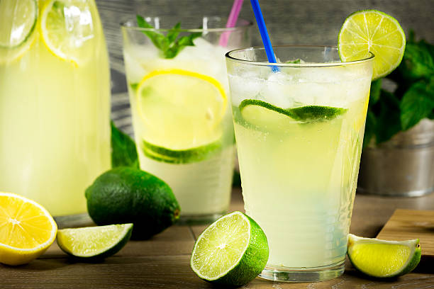 Refreshing lemonade drink and ripe fruits against wooden background