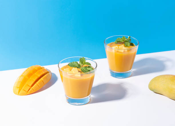 Fresh mango smoothie and ripe mango slice on color background. summer drink. Fresh mango smoothie and ripe mango slice on color background. summer drink. mango smoothie stock pictures, royalty-free photos & images