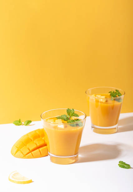 Fresh mango smoothie and ripe mango slice on yellow background. summer drink. Fresh mango smoothie and ripe mango slice on yellow background. summer drink. mango smoothie stock pictures, royalty-free photos & images