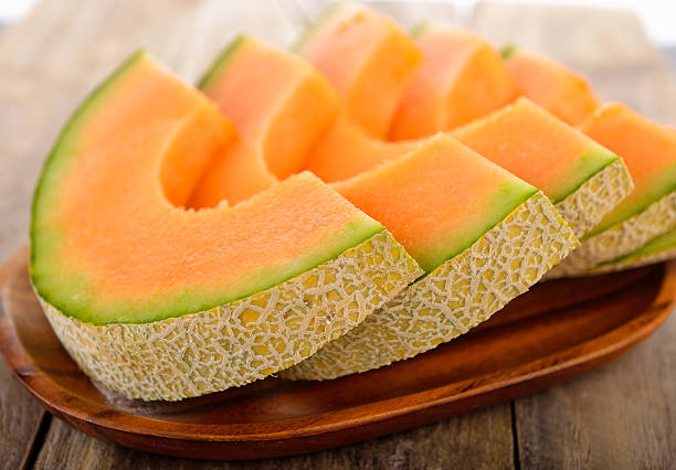 Fresh melons sliced on wooden plate stock photo