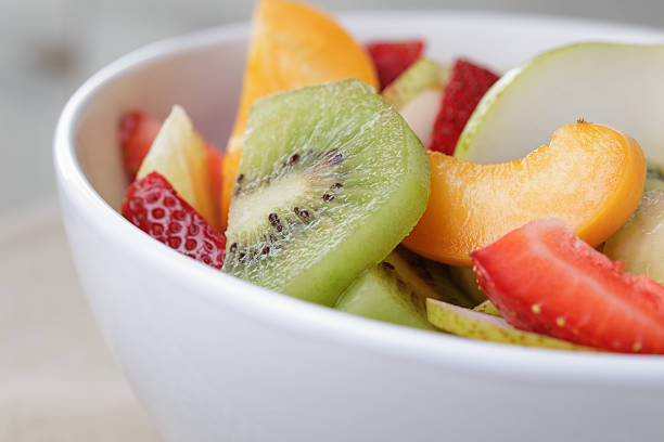 fresh mix fruit salad with strawberry, kiwi and peach, on wood table