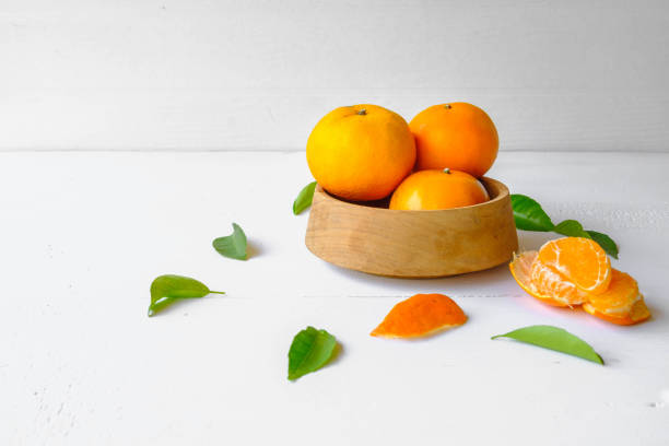 Fresh orange fruit in wooden bowl on white background stock photo