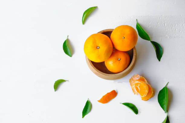 Fresh orange fruit in wooden bowl on white background stock photo
