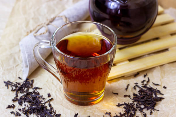 Fresh organic aromatic black tea in the glass cup on light background stock photo