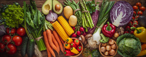 Fresh organic vegetables banner. Toned image of fresh organic vegetables shot from above on rustic wooden table. Vegetables included in the composition are tomatoes, onion, spinach, cucumber, romanesco cauliflower, carrot, avocado, corn, potatoes, green beans, asparagus, radish, mushroom, eggplant, red bell pepper, kale, and cherry tomato. High resolution 24,8Mp studio digital capture taken with SONY A7rII and Zeiss Batis 40mm F2.0 CF lens pepper vegetable stock pictures, royalty-free photos & images