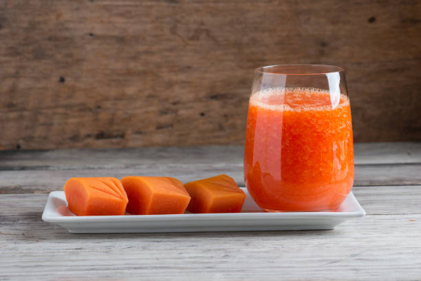 Fresh papaya smoothie juice in glass Fresh papaya smoothie juice in glass on wooden background papaya smoothie stock pictures, royalty-free photos & images