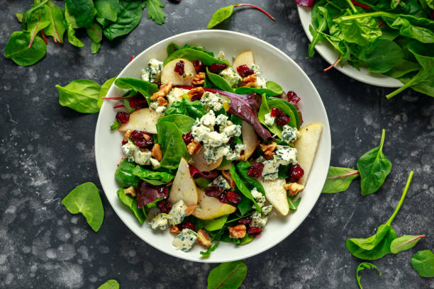 свежие груши, салат из голубого сыра с овощной зеленой смесью, грецкие орехи, клюква. здоровое питание - salad стоковые фото и изображения