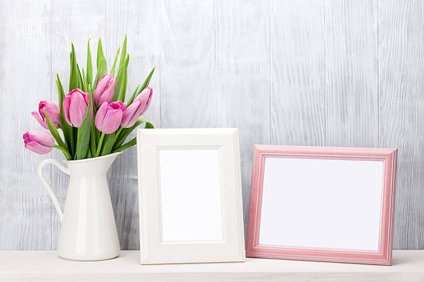 Fresh pink tulips bouquet and photo frames Fresh pink tulip flowers bouquet and blank photo frames with copy space on shelf in front of wooden wall shelf photos stock pictures, royalty-free photos & images