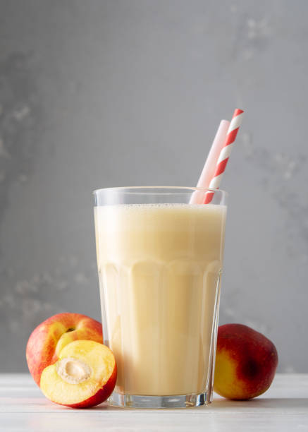 Fresh protein shake with nectarine or peach on a white wooden table. Fresh apricot milkshake. A glass of peach smoothie. Fresh protein shake with nectarine or peach on a white wooden table. Fresh apricot milkshake. A glass of peach smoothie. peach smoothie stock pictures, royalty-free photos & images