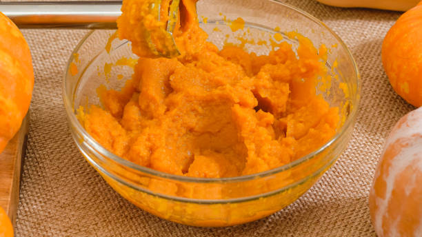 Fresh pumpkin puree in a glass bowl close up on rustic background. Making pumpkin puree from scratch, step by step recipe stock photo