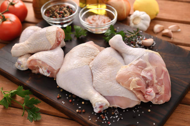 Fresh raw chicken thighs with ingredients for cooking on a wooden cutting board stock photo