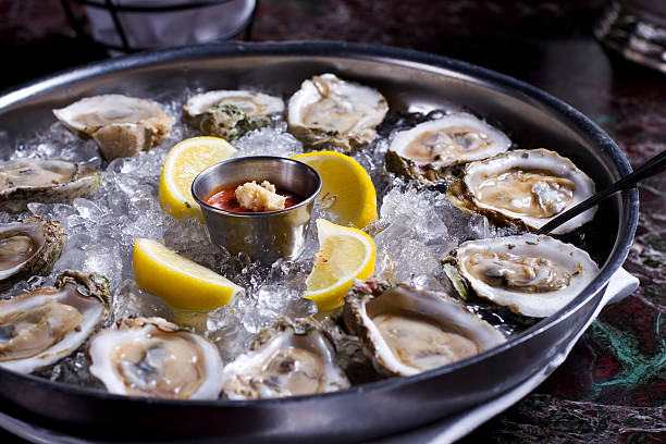 fresh raw oysters with lemons on ice in metal tray - shellfish bildbanksfoton och bilder