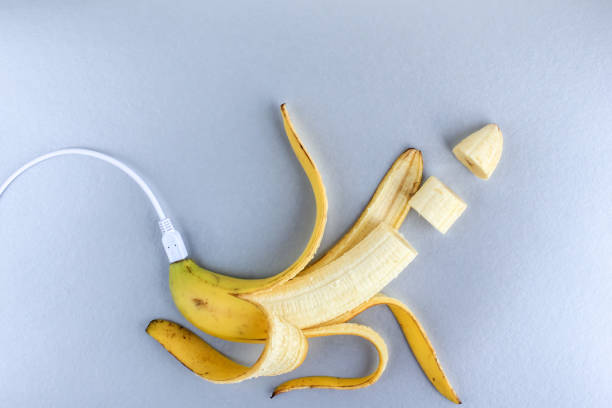 A fresh ripe banana connecting with a white usb charge cable on silver paper textured background. Concept of alternative electricity source, battery charger indicator, energy, healthy food, sex. A fresh ripe banana connecting with a white usb charge cable on silver paper textured background. Concept of alternative electricity source, battery charger indicator, energy, healthy food, sex. Live Sex Streaming stock pictures, royalty-free photos & images