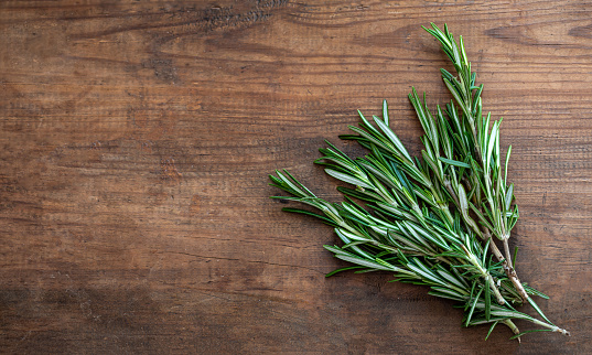 Fresh rosemary herb on a wooden  background. Top view rosemary with  copy space. Cooking concept