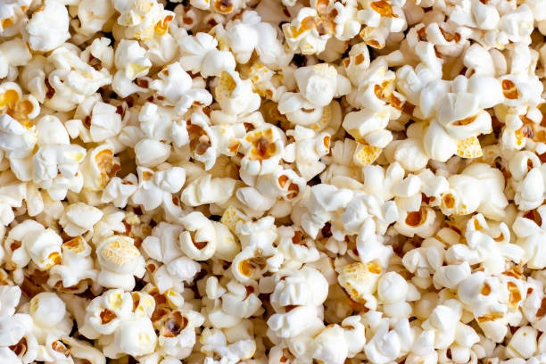 Fresh salted popcorn texture background. Close up top view food pattern photography White and yellow fresh salted popcorn texture background. Close up top view food pattern photography popcorn stock pictures, royalty-free photos & images