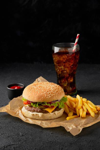 Fresh tasty burger, french fries and soft drink on dark background stock photo