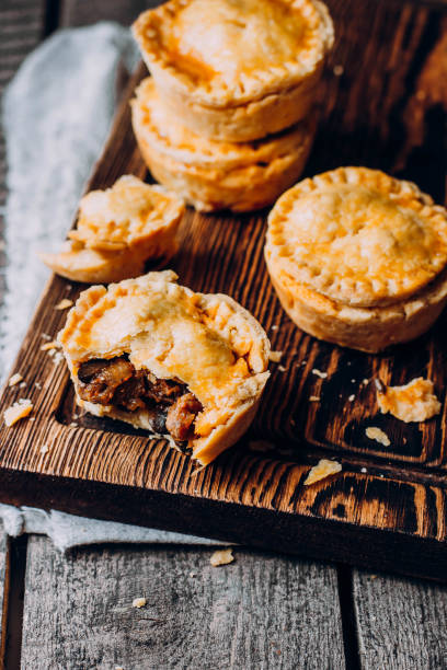 Fresh Traditional Australian meat mini pie on the wooden board on table background, closeup with copy space, rustic style Fresh Traditional Australian meat mini pie on the wooden board on table background, closeup with copy space, rustic style meat pie stock pictures, royalty-free photos & images