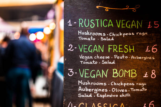 Fresh vegan vegetarian take out food stall at street food market Color close up image depicting a vegan take out food stall at an outdoor food market in London, UK. Focus is on the sign listing the different varieties of vegetarian and vegan food on offer. People and food market beyond are attractively defocused, leaving room for copy space. plant based menu stock pictures, royalty-free photos & images